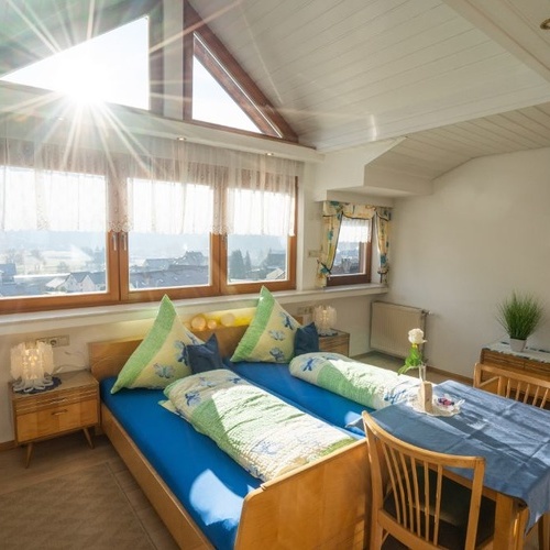 Doppelbett mit großer Fensterfront im Hintergrund und kleinem Tisch - Doppelbett mit großer Fensterfront im Hintergrund und kleinem Tisch -