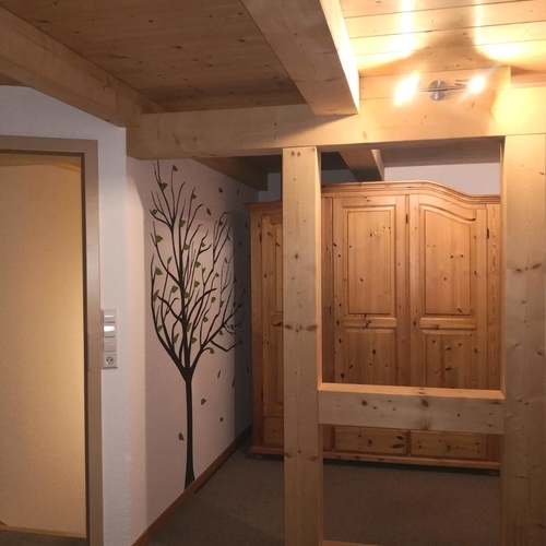 Blick durch Holzbalken, als Raumteiler, auf einen gro&szlig;en Holzschrank  - 