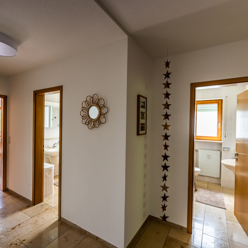 Blick vom Flur auf zwei ge&ouml;ffneteT&uuml;ren des Badezimmers und der WC-T&uuml;re - 